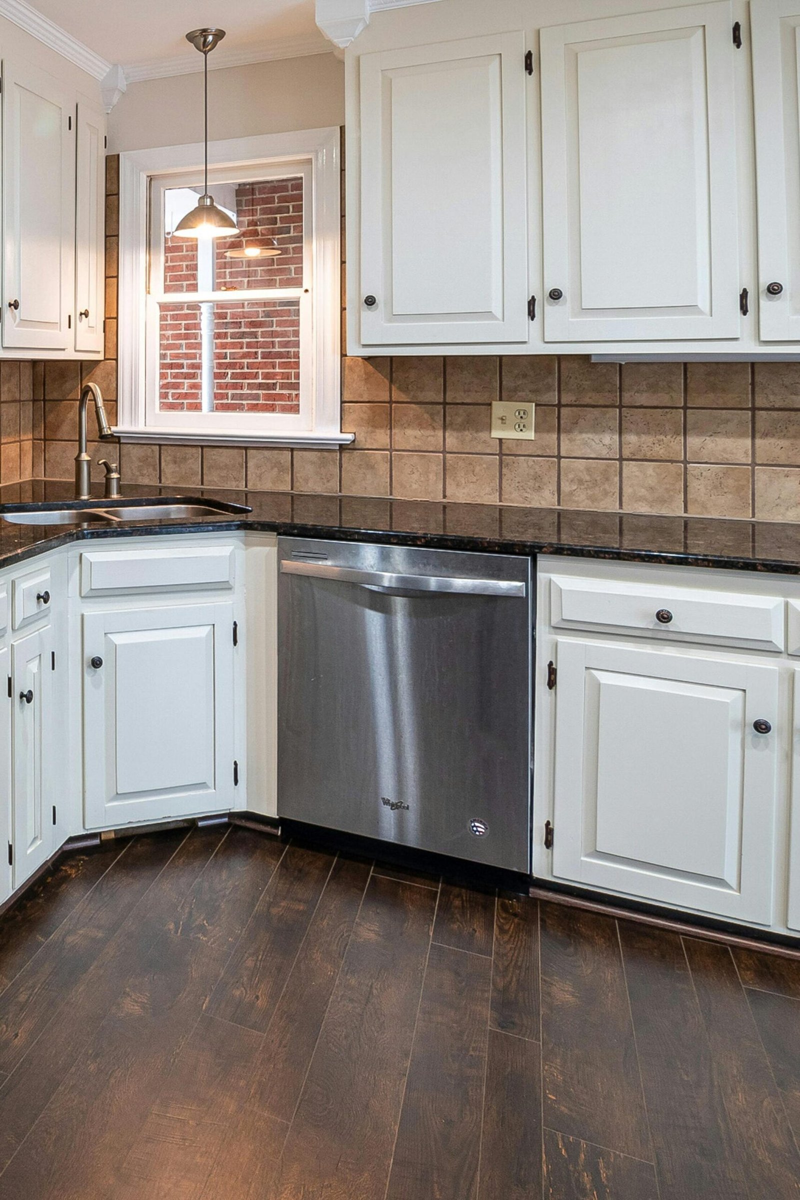 Spacious kitchen featuring white cabinets, stainless steel appliances, and wooden flooring.