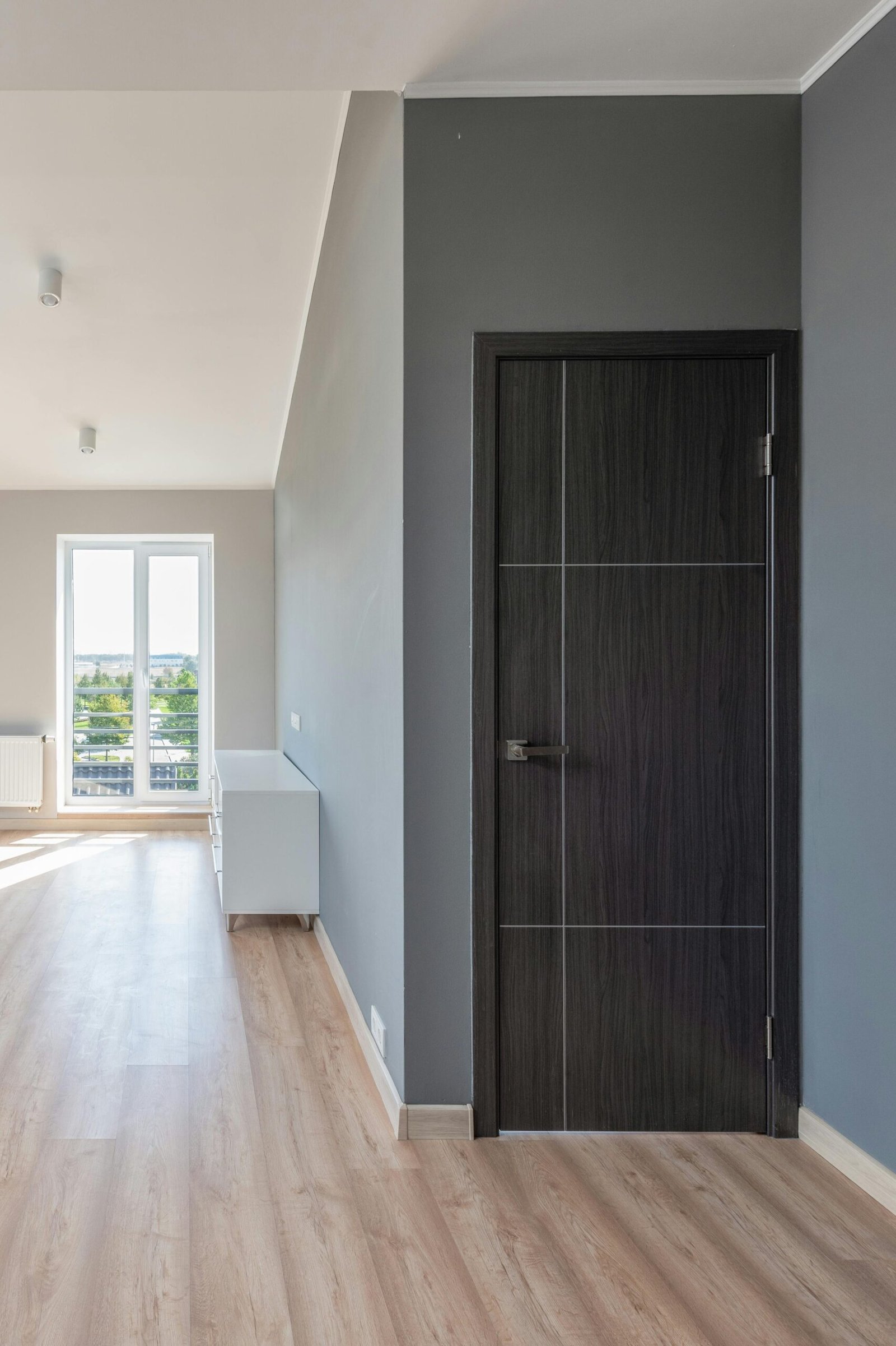 Spacious empty room with wooden flooring and large windows for ample natural light.