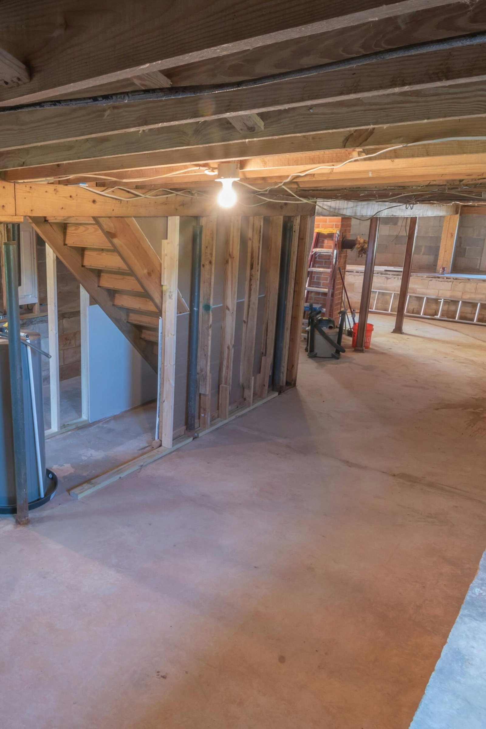 Empty basement with exposed beams and plumbing pipes, ideal for renovation.